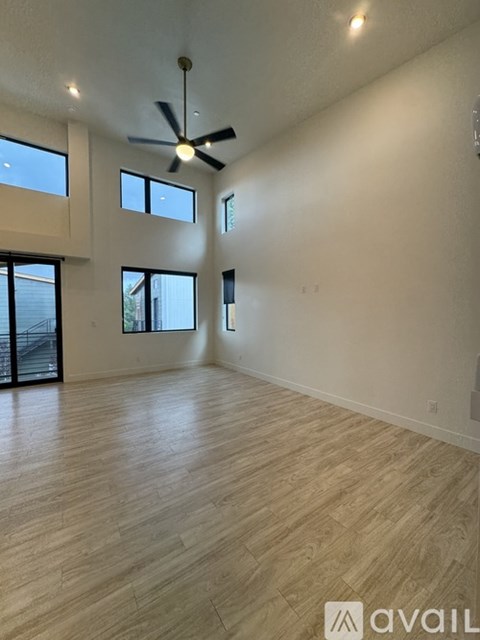 A spacious room with wooden flooring and a ceiling fan.