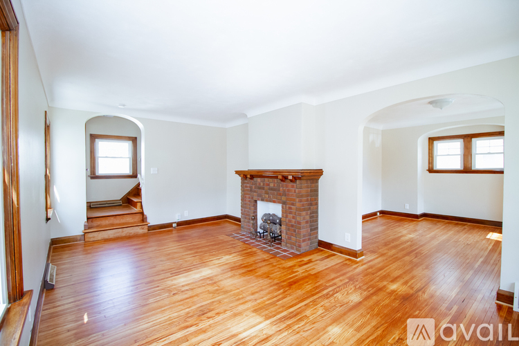 A large empty room with a fireplace and wooden floors.