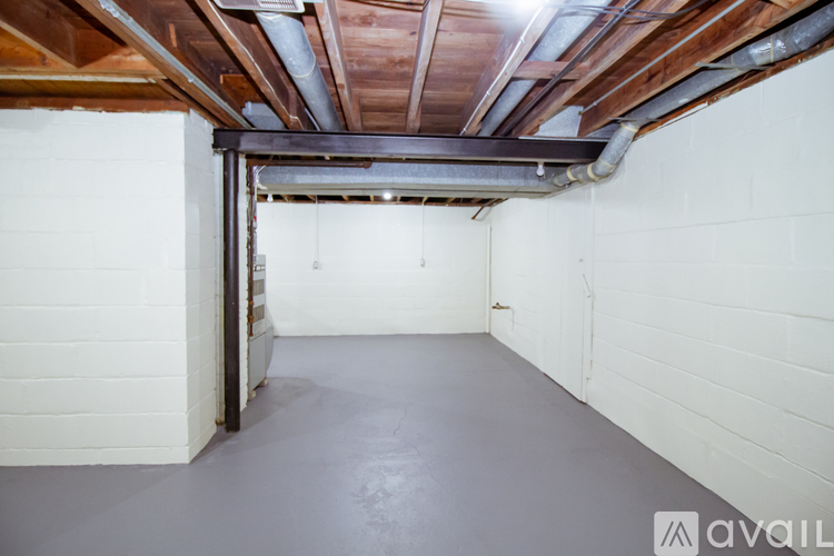 A spacious attic room with wooden beams on the ceiling and white walls.