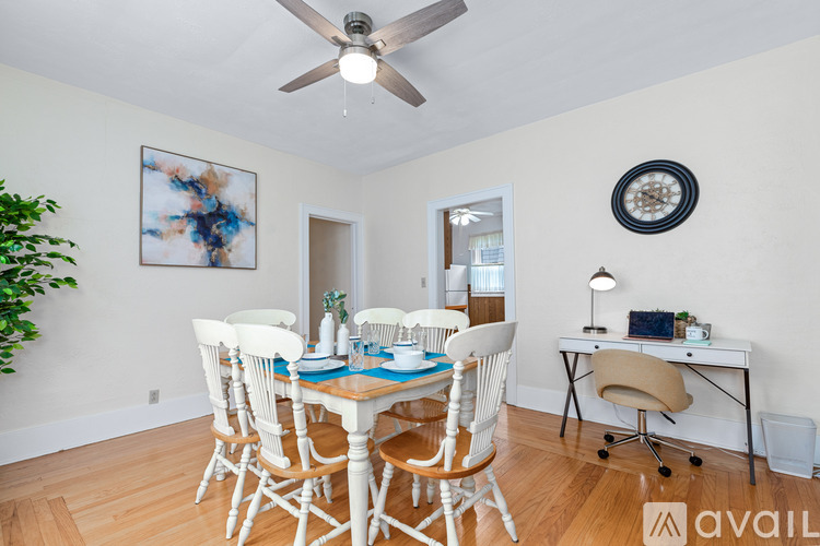 A dining room with a table set for four and a ceiling fan.