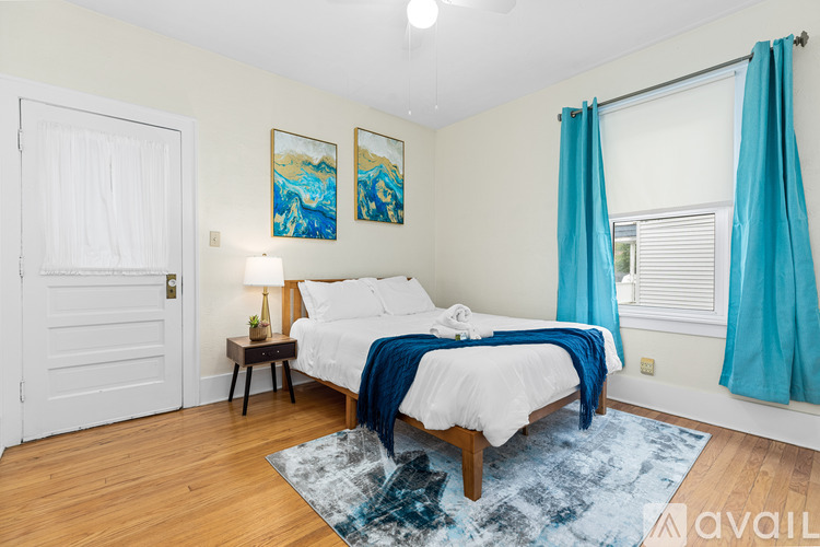 A bedroom with a bed, nightstand, and two paintings on the wall.