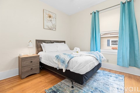 A bedroom with a bed, nightstand, and a framed picture on the wall.