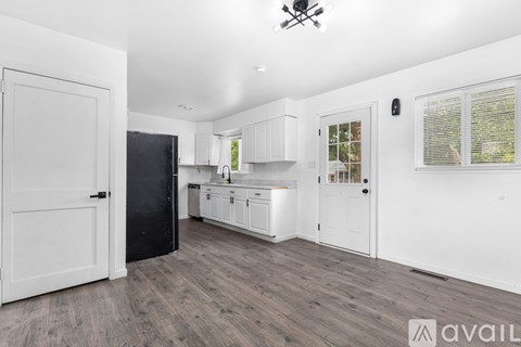 A kitchen with white cabinets and a black refrigerator is available for rent.