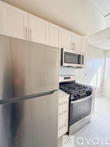 A kitchen with a stainless steel refrigerator and a black stove top oven.