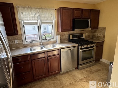 A kitchen with brown cabinets and a stainless steel refrigerator.