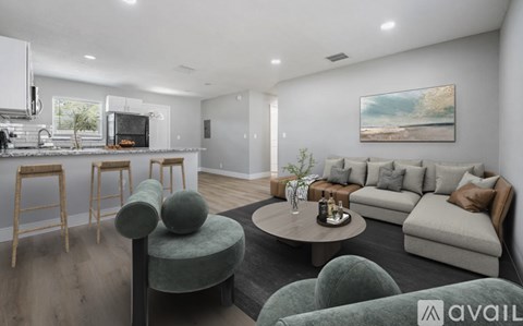 A modern living room with a grey couch, a round green chair, and a coffee table with a vase and candles on it.