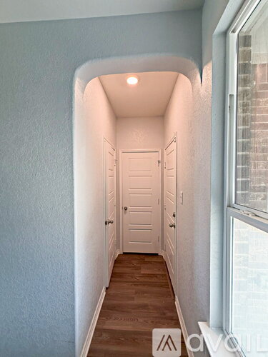 A hallway with a white door and wooden floor.
