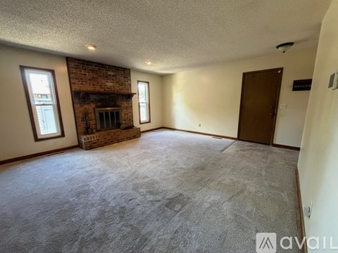A spacious room with a brick fireplace and a door on the right side.