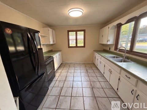 A kitchen with black appliances and white cabinets.