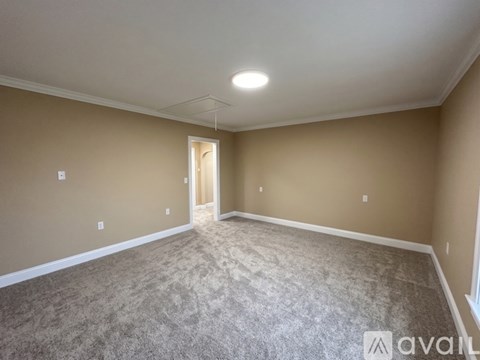 A spacious room with carpeted floor and a doorway leading to another room.