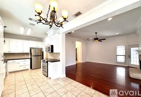 A well-lit kitchen with a refrigerator, oven, and a dining table with chairs.