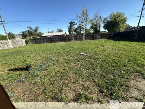 A backyard with a fence and a grassy area.