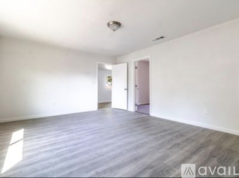 A spacious room with a wooden floor and white walls.