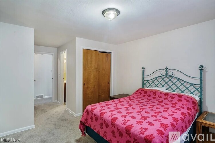 A bedroom with a bed, nightstand, and a door.