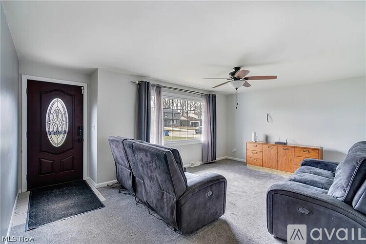 A living room with grey couches and a ceiling fan.