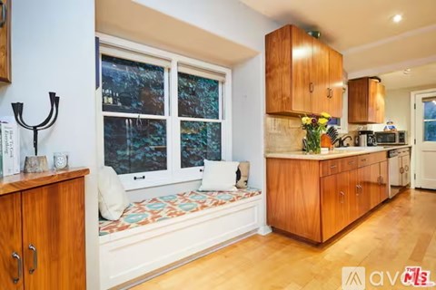 A kitchen with wooden cabinets and a bench seat.