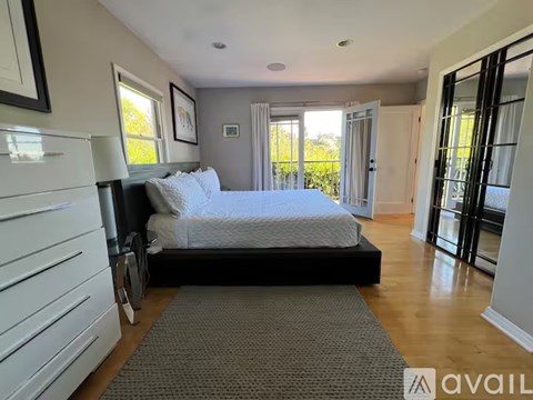A bedroom with a large bed and a balcony.