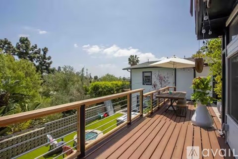 A wooden deck with a table and chairs overlooking a pool.