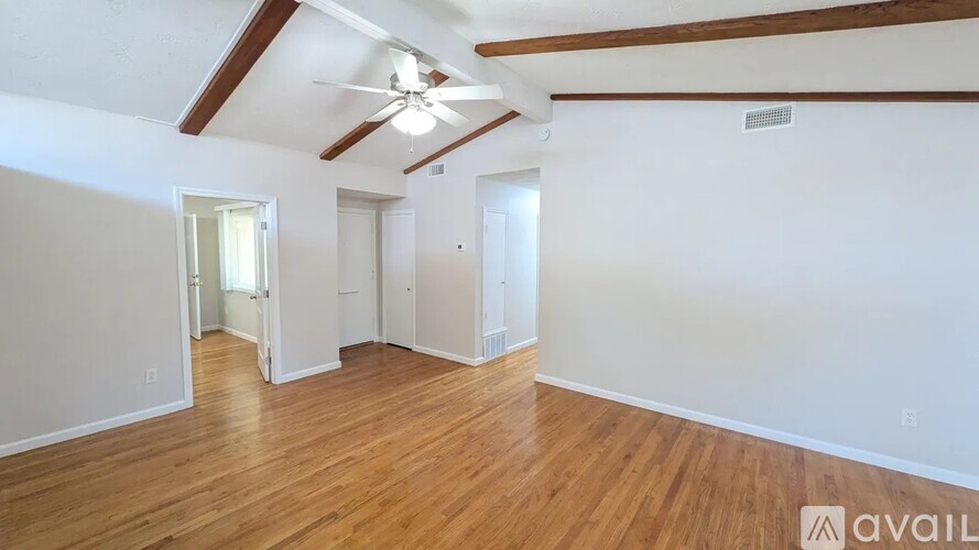 A room with wooden floors and white walls, with a ceiling fan and a light fixture.