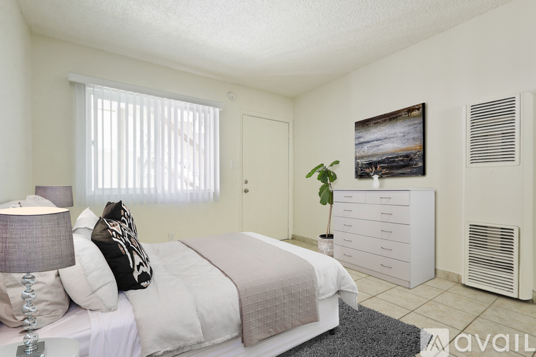A bedroom with a bed, nightstand, and a painting on the wall.