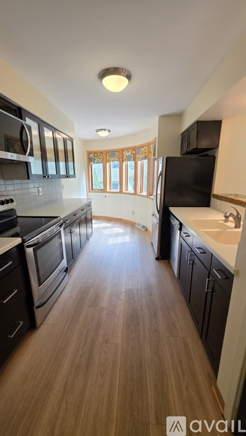 A kitchen with wooden floors and black appliances.