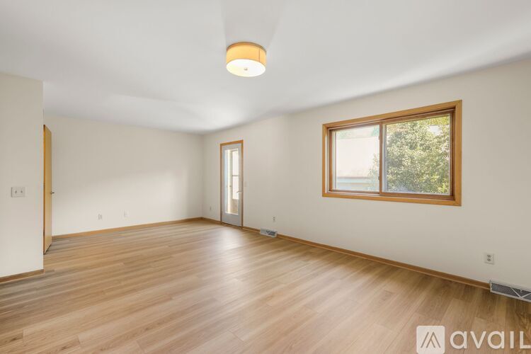 A room with wooden floors and a window with a view of trees.