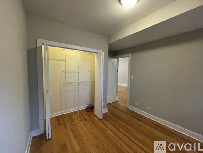 A room with wooden floors and a white wall with a doorway leading to another room.