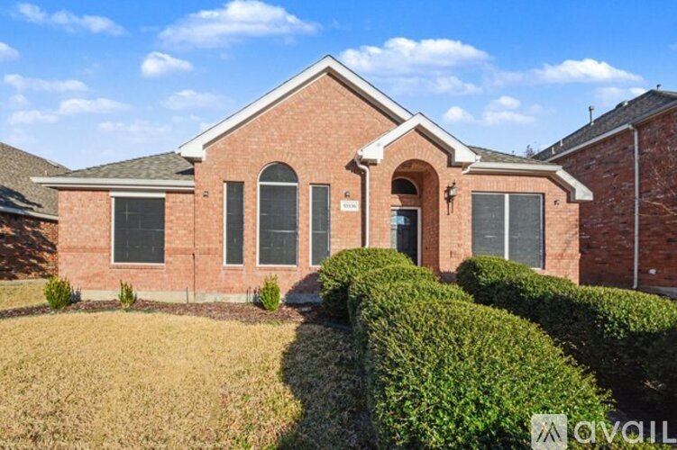 A red brick house with a hedge in front.