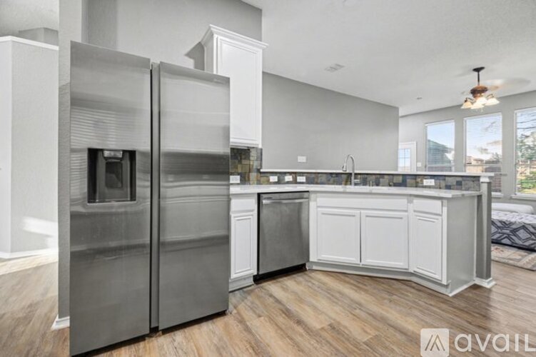 A modern kitchen with a stainless steel refrigerator and wooden flooring.