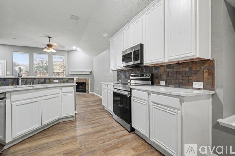 A kitchen with white cabinets and a brick backsplash.
