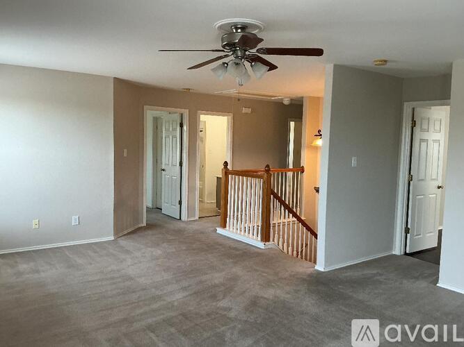 A living room with a ceiling fan and a staircase.