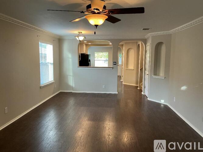 A spacious room with a ceiling fan and wooden flooring.