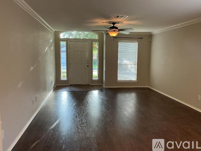 A room with a ceiling fan and wooden flooring.