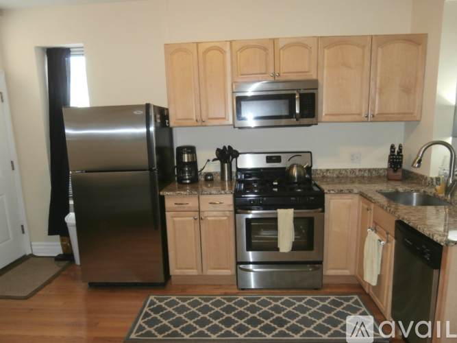 A kitchen with wooden cabinets and a black fridge.