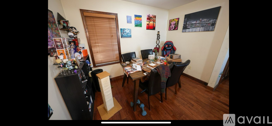A room with a desk, chairs, and a fridge.
