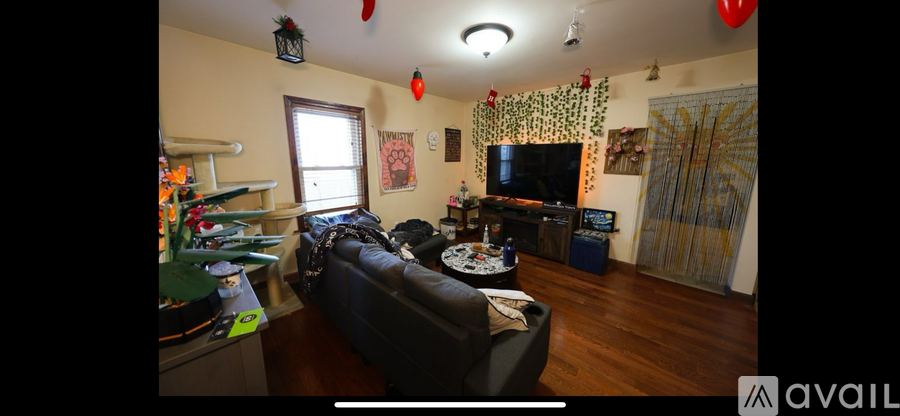 A living room with a couch, a television, and a dartboard.