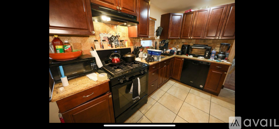 A kitchen with brown cabinets and black appliances.