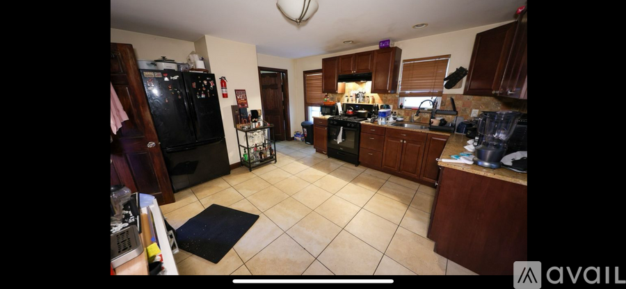 A kitchen with a black fridge and a black mat on the floor.