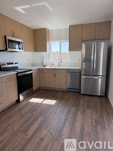 A kitchen with wooden cabinets and a stainless steel refrigerator.