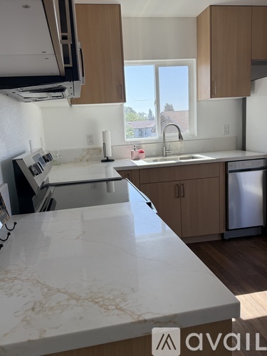 A kitchen with a marble counter top and wooden cabinets.