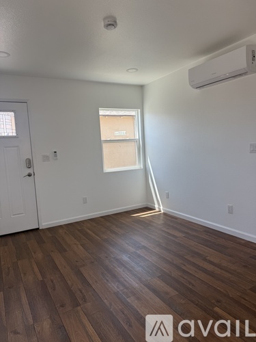 A room with wooden floors and a window with blinds.