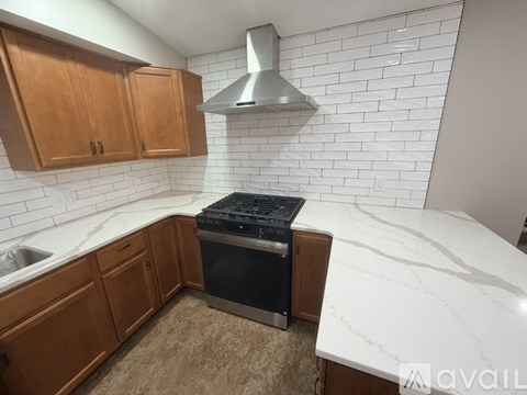 A kitchen with a white marble countertop and a black stove top oven.