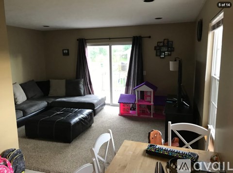 A living room with a black couch and a pink dollhouse.