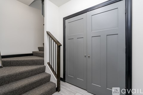 A staircase with a wooden banister leads to a landing with a grey door.