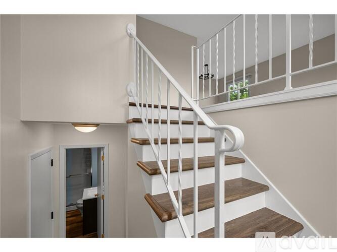 A white staircase with wooden steps and a metal railing.