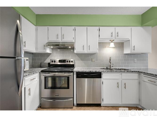 A kitchen with white cabinets and a green backsplash.