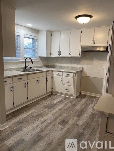 A kitchen with white cabinets and a grey floor.