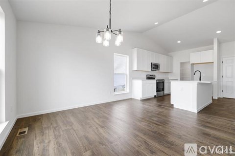 A spacious kitchen with white cabinets and a wooden floor.