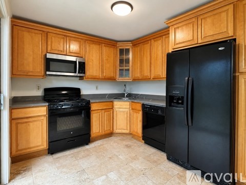 A kitchen with wooden cabinets and black appliances.