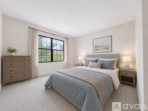 A bedroom with a large bed, a dresser, and a window with a view of trees.